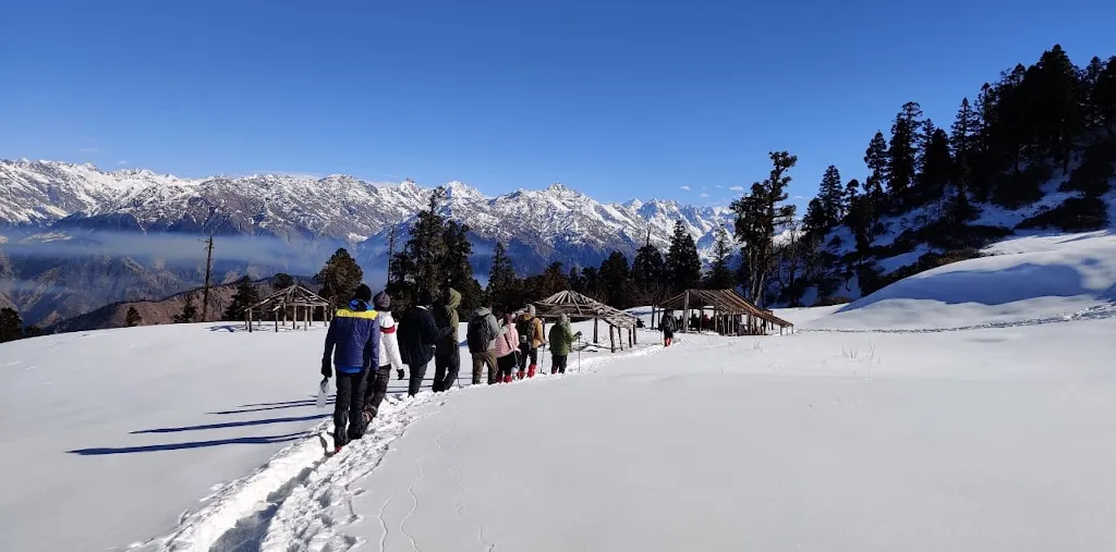 Trekkers on snowy trail with Himalayan panorama