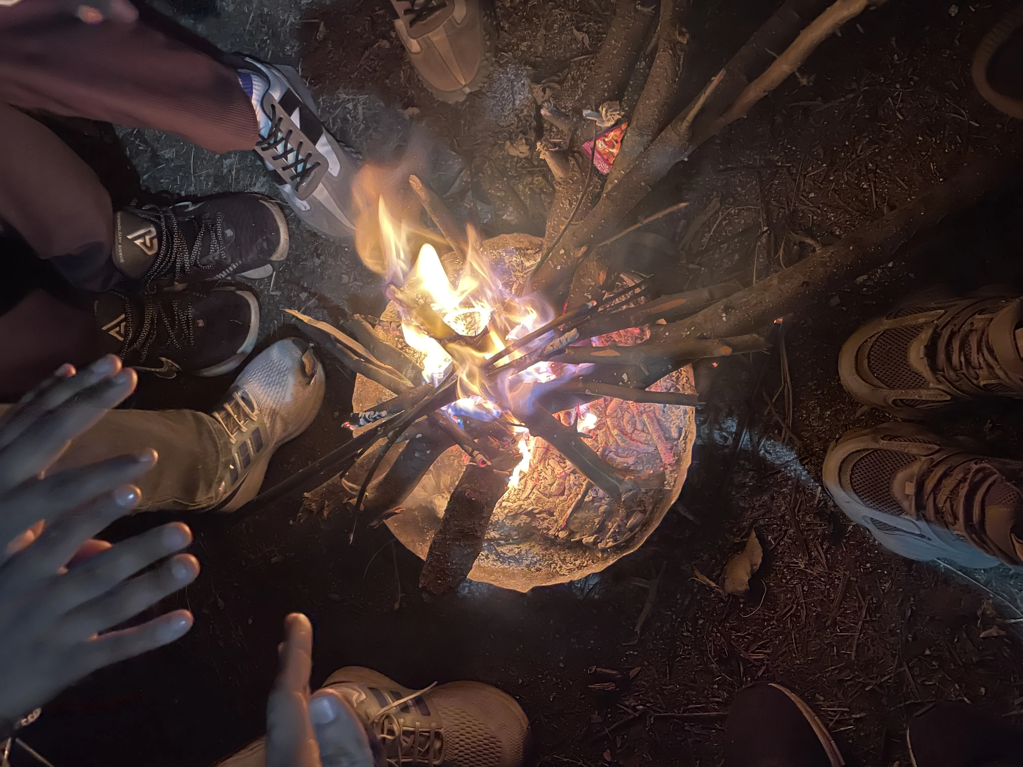 Trekkers warming hands around bonfire